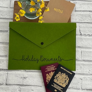 May include: Green felt envelope with the text "Holiday Documents" on the front. Two British passports are visible inside the envelope.