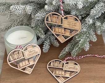 May include: Three wooden heart-shaped Christmas ornaments with a bookshelf design. One ornament says "Merry Christmas", another says "Just a girl who loves Books", and the third says "Camilla". Each ornament has a red and white string for hanging.