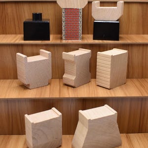 May include: Assortment of wooden train track pieces, including bridges, tunnels, and straight track sections. The pieces are made of natural wood and have a light brown color.