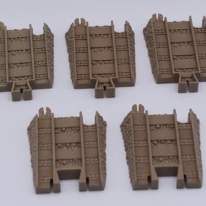 Pode incluir: Cinco peças de trilhos de trem de brinquedo de plástico marrom. Cada peça tem formato retangular com superfície texturizada e uma série de linhas paralelas que representam os dormentes. As peças têm uma estrutura semelhante a uma ponte na parte inferior.