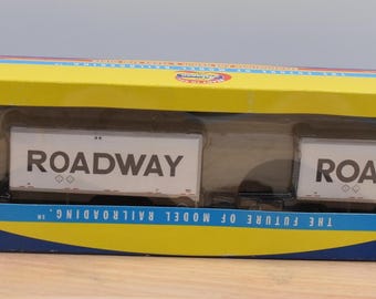 May include: A model semi-truck with two white trailers featuring the word ROADWAY in black lettering, enclosed in a yellow and blue cardboard box with a clear plastic window. The box displays the text THE FUTURE OF MODEL RAILROADING.