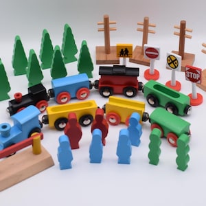 May include: A wooden toy train set with colorful train cars, trees, people, and road signs. The set includes a blue train, a black train, a red train, and a green train. The set also includes a crossing gate.