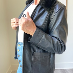 May include: A black leather jacket with a faux fur collar. The jacket has a zipper closure and a pocket on the left side.