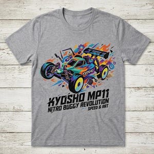 May include: A gray t-shirt featuring a colorful graphic of a Kyosho MP11 nitro buggy race car. The design includes the text "KYOSHO MP11 NITRO BUGGY REVOLUTION SPEED & ART" in a bold font, with vibrant hues of blue, orange, and purple.