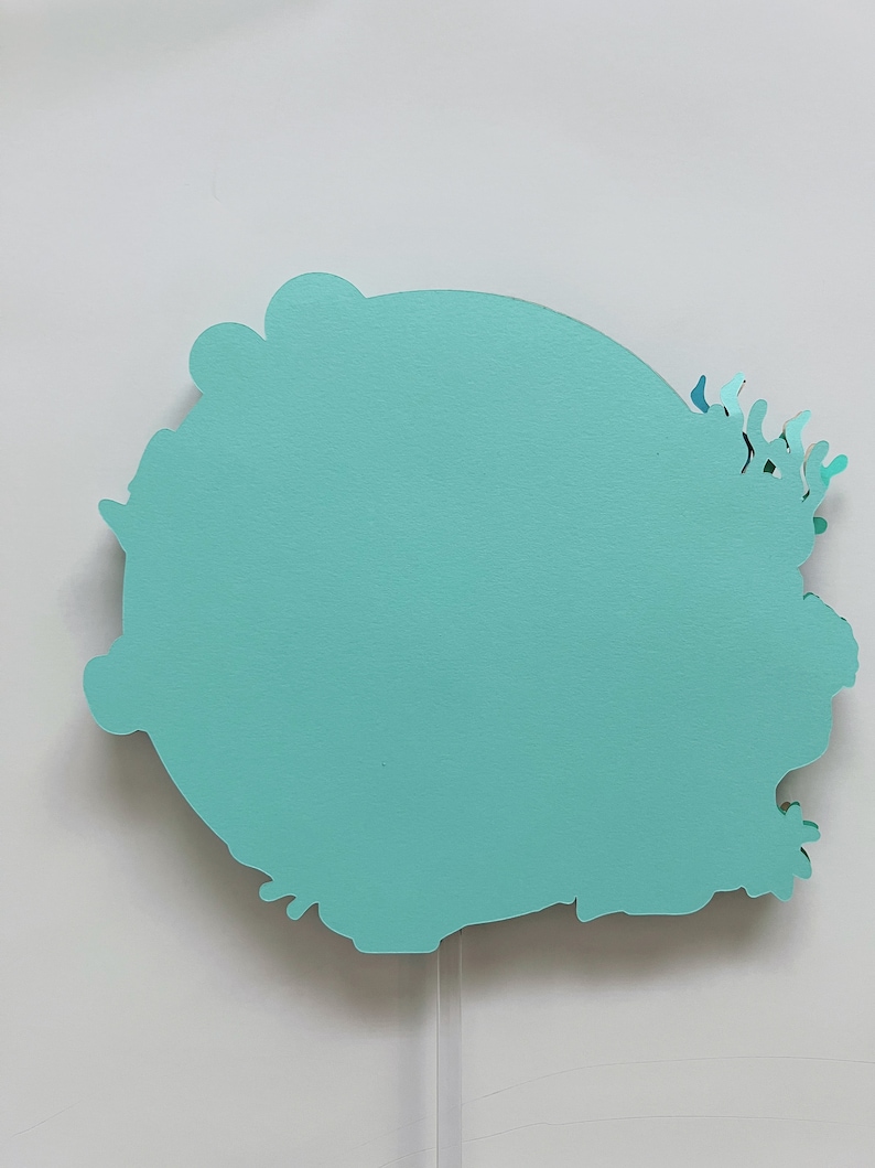 May include: A teal blue paper cutout of a stylized flower with a white background.