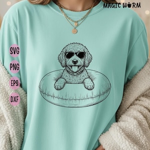 May include: A light mint green t-shirt featuring a black line art graphic of a curly-haired dog wearing sunglasses and sitting inside a circular pool float. The text MAGIC WORM appears in the top right corner, with SVG, PNG, EPS, and DXF labels.