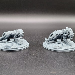 May include: Two gray painted miniature figures of a panther and a tiger, both standing on round bases.
