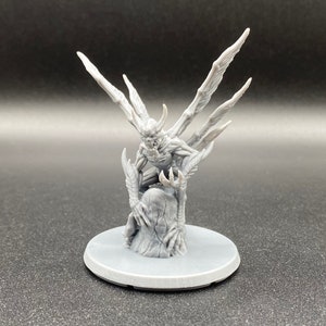 May include: A gray, detailed miniature of a winged demon with sharp claws and fangs, perched on a rocky base. The demon has a menacing expression and appears to be in a crouched position.