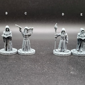 May include: Six gray painted miniature figures of robed figures holding various objects, including a book, a staff, a dagger, and a scroll. The figures are standing on round bases.