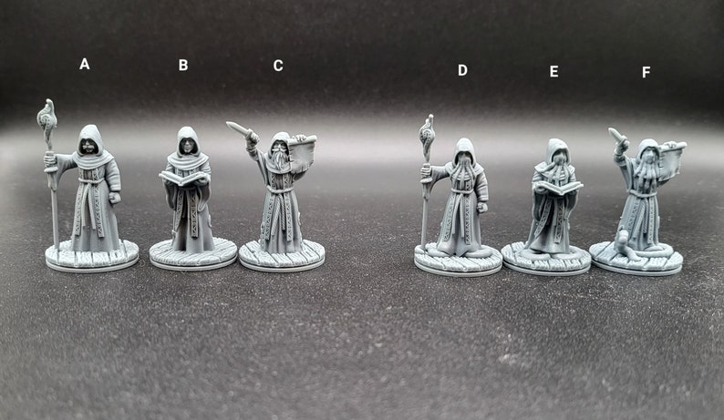 May include: Six gray painted miniature figures of robed figures holding various objects, including a book, a staff, a dagger, and a scroll. The figures are standing on round bases.