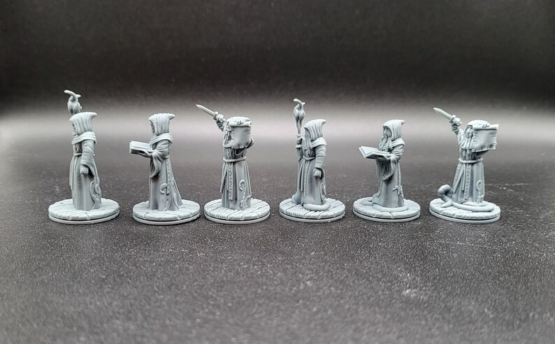 May include: Seven gray plastic miniature figures of robed figures with different poses and accessories, including a staff, a book, and a sword. The figures are standing on round bases.