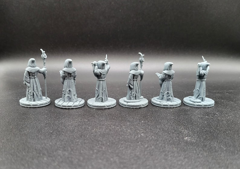 May include: Seven gray plastic miniature figures of robed wizards with staffs, each standing on a round base.