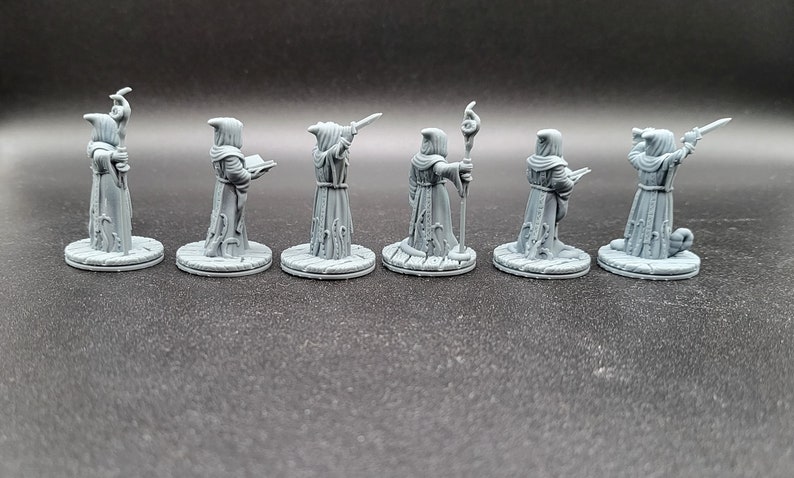 May include: Seven gray painted miniature figures of robed wizards, each holding a different magical item, standing on round bases.