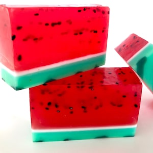 May include: Three bars of watermelon-scented soap. The soap is red with black seeds and a green and white stripe.
