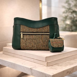 May include: A green handbag with a tweed center panel and a smaller matching coin purse. The handbag has a gold zipper and a structured shape. The coin purse has a small handle and a gold clasp. Both items are displayed on a white surface.