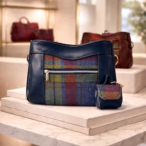 May include: A navy blue handbag with a plaid front panel and a small matching coin purse. The handbag has a zipper closure and gold-colored hardware. Other handbags are visible in the background.