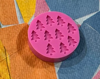 May include: Pink silicone mould with 12 individual cavities shaped like Christmas trees.