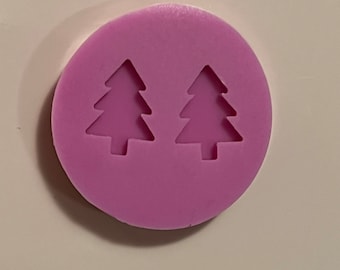 May include: A purple silicone mould with two Christmas tree shapes. The mould is round and has a smooth surface.
