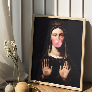 Pu&ograve; includere: Una stampa incorniciata di un dipinto che ritrae una donna con una corona e una veste scura, con una gomma da masticare rosa in bocca. Lo sfondo &egrave; scuro.