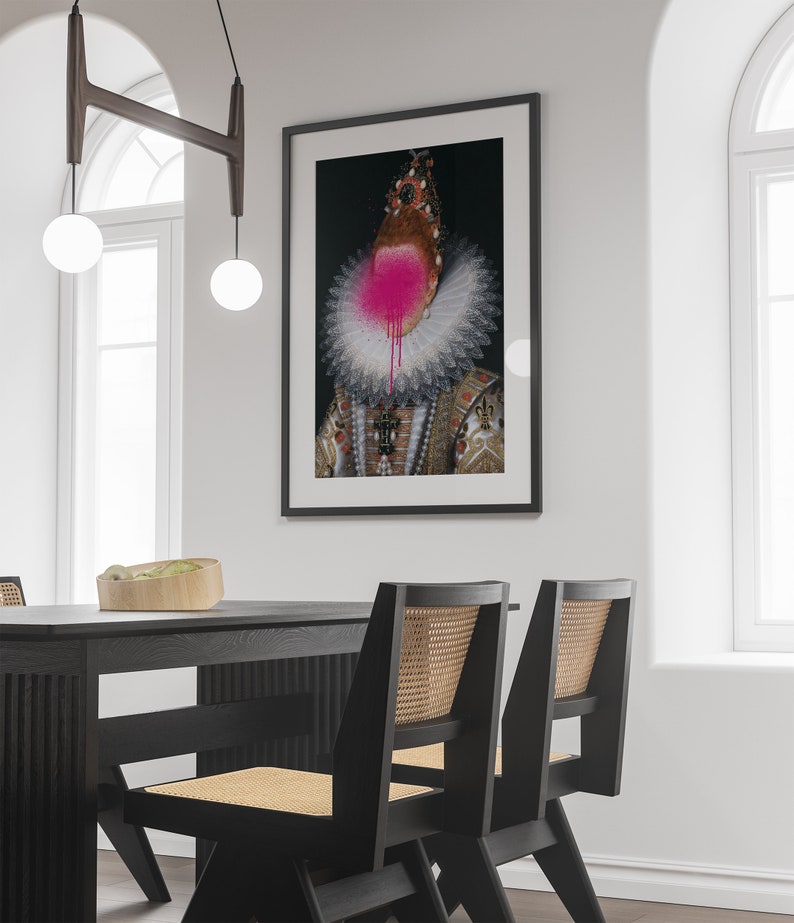 May include: A black framed print of a portrait of a person wearing a large white ruff collar and a crown. The person's face is obscured by a pink spray paint splatter.