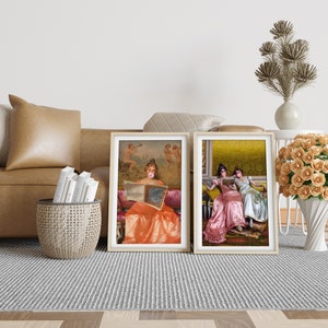 May include: Two framed paintings of women in vintage dresses. The woman in the left painting is wearing a peach dress and holding a book. The woman in the right painting is wearing a pink dress and sitting next to another woman in a white dress.