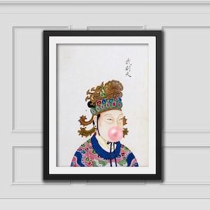 Puede incluir: Obra de arte enmarcada que presenta una figura asiática tradicional con una burbuja de chicle. La figura lleva un tocado ornamentado y túnicas coloridas. La obra está sobre un fondo blanco y enmarcada en negro.