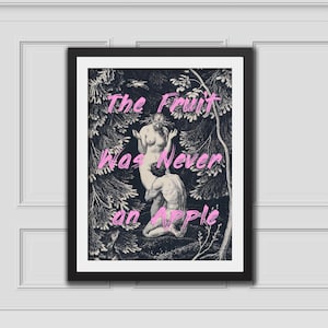Könnte beinhalten: Ein gerahmter Schwarz-Weiß-Druck mit einer Gravur von zwei Figuren in einer Waldlandschaft, überlagert mit dem Text "The Fruit Was Never an Apple" in leuchtend rosa Schreibschrift. Das Kunstwerk befindet sich in einem schlichten schwarzen Rahmen.