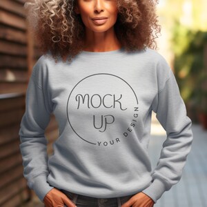 Puede incluir: Una sudadera gris claro con un círculo negro y el texto "YOUR DESIGN - MOCK UP" en una fuente manuscrita.