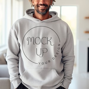 Puede incluir: Una sudadera con capucha gris con un gráfico circular que dice "YOUR DESIGN" y "MOCK UP" en una fuente manuscrita.