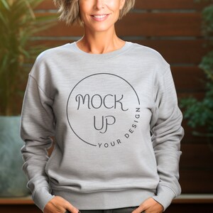Puede incluir: Una sudadera gris con un círculo negro y el texto "YOUR DESIGN" y "MOCK UP" dentro del círculo.