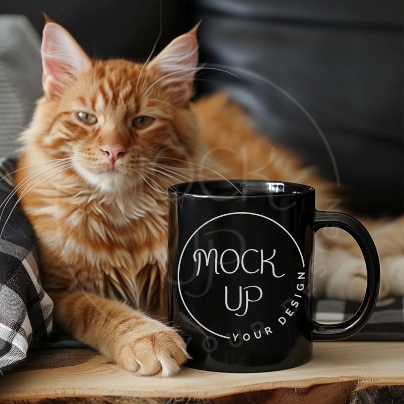 Peut inclure: Une tasse en c&eacute;ramique noire avec un cercle blanc et le texte "Mock Up Your Design" sur une surface en bois. Un chat roux est assis &agrave; c&ocirc;t&eacute; de la tasse.