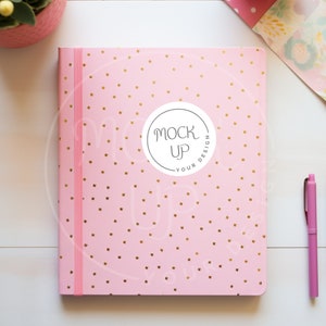 May include: Pink notebook with a gold polka dot pattern and a white circle with the text "Mock Up Your Design".