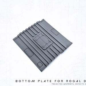 Può includere: Piastra inferiore rettangolare grigio scuro per Rogal Dorn, con una serie di creste parallele e un pannello di accesso centrale rettangolare con una porta a cerniera. La piastra presenta diversi dettagli rettangolari più piccoli.