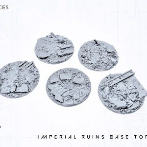 Puede incluir: Cinco bases circulares grises "Imperial Ruins Base Topper", cada una con un diseño texturizado único de escombros y escombros. El texto "5X PIECES SET A" está en la parte superior izquierda. El texto "IMPERIAL RUINS BASE TOPPER" está en la parte inferior.