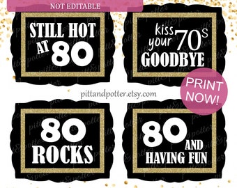May include: Four printable 80th birthday party signs with gold glitter accents. The signs say "Still Hot at 80", "Kiss Your 70s Goodbye", "80 Rocks", and "80 and Having Fun".