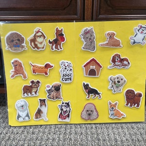 May include: A yellow sheet with various dog stickers on it. The stickers feature different breeds of dogs in various poses, including a dachshund, a pug, a dalmatian, a golden retriever, a corgi, and a bulldog. The stickers are all colorful and have a cartoonish style.