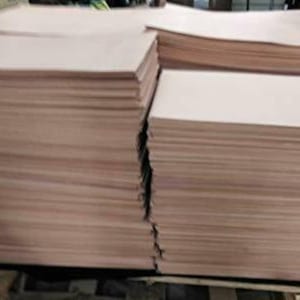 May include: Stacks of light brown paper sheets, likely for printing or crafting. The paper appears to be a neutral tone, with visible edges indicating individual sheets. The image shows multiple stacks, suggesting a bulk quantity of the paper.