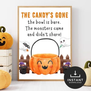 May include: A framed Halloween-themed print with the text "THE CANDY'S GONE" and a smiling pumpkin bucket illustration. The print is surrounded by plush pumpkins in various sizes and a white wooden crate.