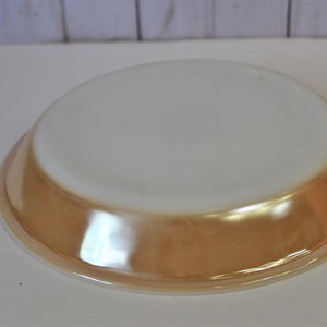 May include: A white pie plate with a gold rim. The plate is made of glass and has a smooth, glossy finish.