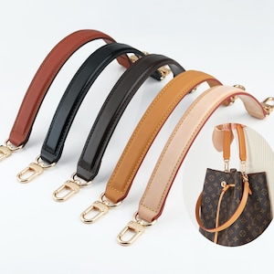 Op de afbeelding: Vijf gebogen tashengsels in diverse kleuren, waaronder bruin, zwart, donkerbruin, lichtbruin en beige. Elk hengsel is voorzien van goudkleurige metalen karabijnhaken aan beide uiteinden. Een cirkelvormige inzet toont een bruin hengsel aan een tas.