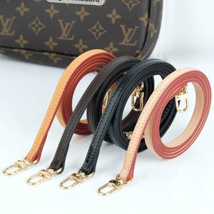 May include: Four leather purse straps in tan, brown, black, and pink with gold-colored clasps. The straps are coiled and displayed against a white background. A brown purse with a logo is visible in the background. Text on the image reads "Bag not included."