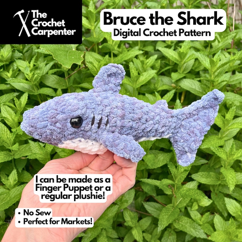 K&ouml;nnte beinhalten: Ein geh&auml;kelter Hai in Blau- und Lilat&ouml;nen, mit wei&szlig;em Bauch und schwarzen Augen. Der Text "Bruce the Shark Digital Crochet Pattern" steht &uuml;ber dem Hai. Der Text "I can be made as a Finger Puppet or a regular plushie!" ist ebenfalls sichtbar.