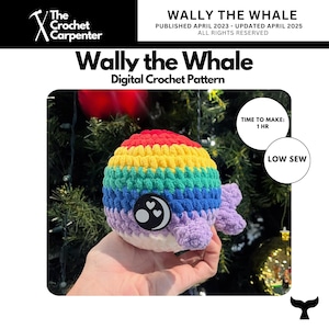 May include: A colourful crocheted whale toy with a rainbow body, white belly, and purple fins. The toy features a black and white emblem with hearts. The image includes the text "Wally the Whale" and "Digital Crochet Pattern". The text "TIME TO MAKE: 1 HR" and "LOW SEW" is also visible.