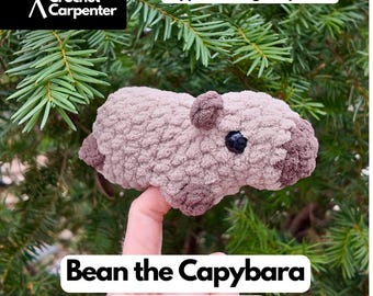 May include: A crocheted capybara plushie in shades of tan and brown, with a black eye. The text "Bean the Capybara" and "Digital Crochet Pattern" are displayed. The image also includes the text "I can be made as a Finger Puppet or a regular plushie!"