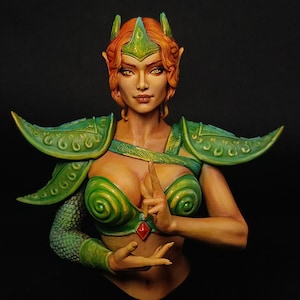May include: A detailed bust of a fantasy female figure with red hair and green armour. The figure wears a green headdress, shoulder armour, and a bodice with a spiral design. A red gem hangs between her hands, which are in a prayer-like pose.
