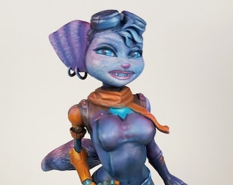 May include: A blue and purple anthropomorphic cat figurine with orange scarf and goggles. The figurine has a detailed face with blue eyes and a toothy grin.