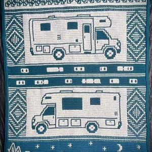 K&ouml;nnte beinhalten: Ein Wandbehang aus H&auml;kelarbeit mit einem blaugr&uuml;nen Hintergrund und wei&szlig;en Stichen. Das Design zeigt zwei wei&szlig;e Wohnmobile mit dem Text "TAKE THE SCENIC ROUTE" oben. Der untere Teil des Designs zeigt eine wei&szlig;e Bergkette, B&auml;ume und ein Geb&auml;ude mit dem Text "PUB" dar&uuml;ber.