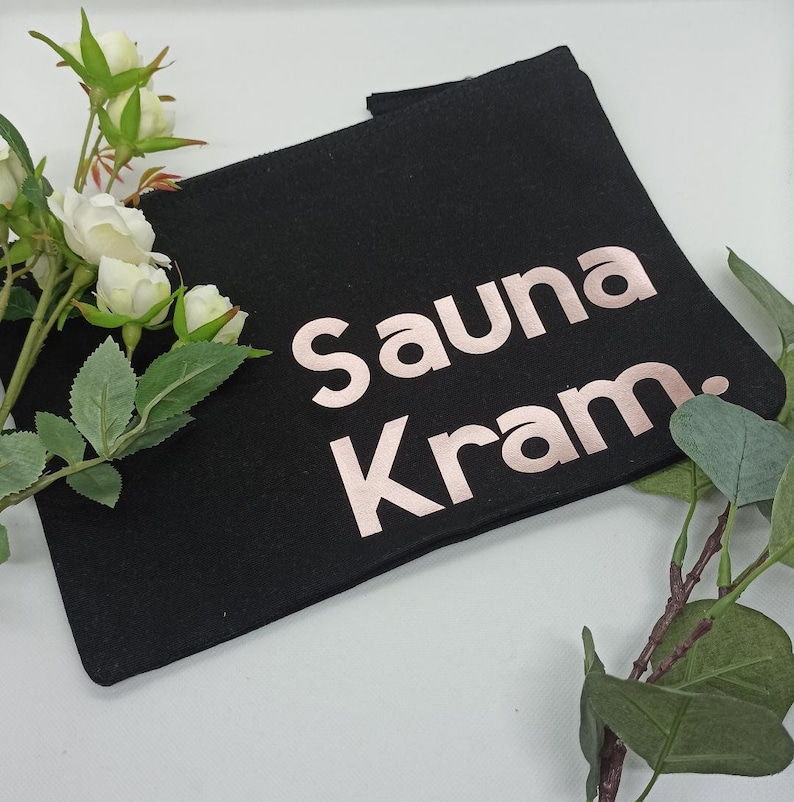 May include: Black canvas zippered pouch with the text "Sauna Kram" in rose gold lettering.