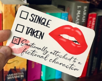 May include: White sticker with a red lip graphic and three checkboxes. The checkboxes are labeled "Single", "Taken", and "Emotionally attached to a fictional character". The checkbox for "Emotionally attached to a fictional character" is checked with a red X.