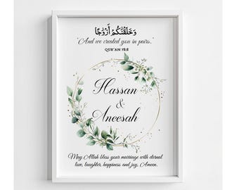 May include: Framed print with the names "Hassan & Aneesah" in elegant script, surrounded by a gold ring and green foliage. The print includes Arabic calligraphy and the English phrase "And we created you in pairs." A wedding or anniversary gift.